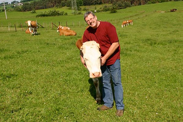 Landwirt mit glücklicher Kuh auf Wiese